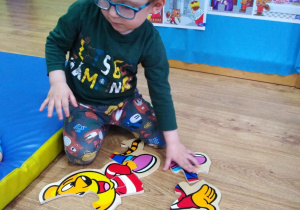 Chłopczyk układa Myszkę Miki z drewnianych elementów.
